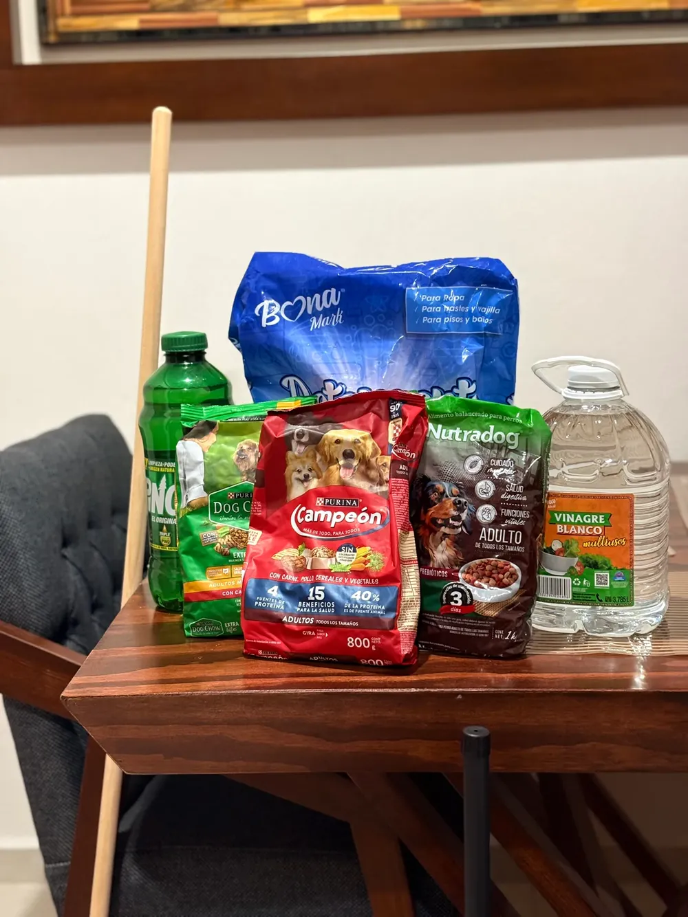 Bolsas de croqueta, detergente, vinagre y una escoba sobre una mesa, listos para entregar.
